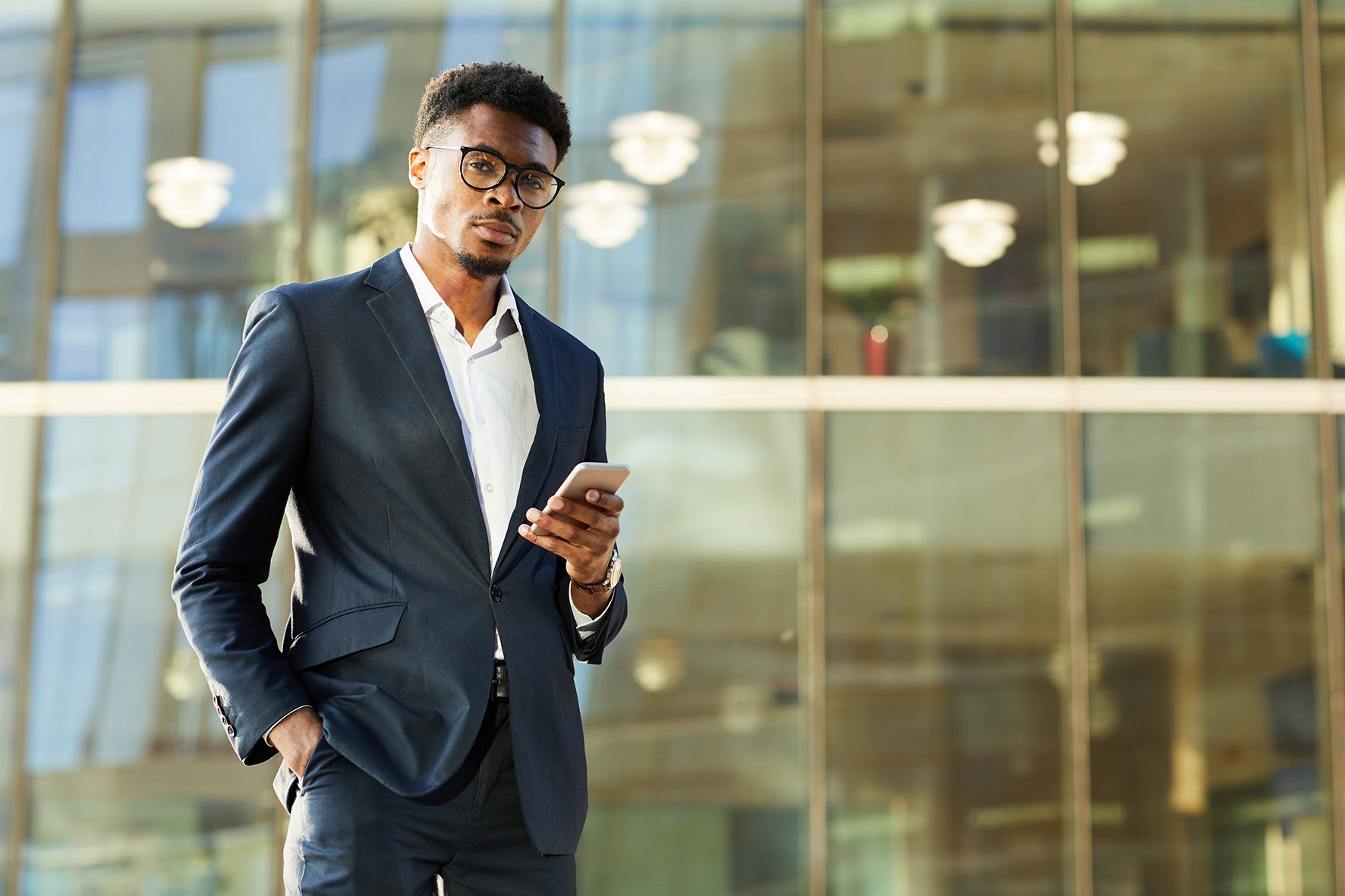 portrait-serious-handsome-young-afroamerican-man-dark-suit-holding-hand-pocket-using-sm